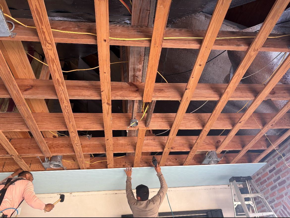 A man is hanging a piece of wood from the ceiling.