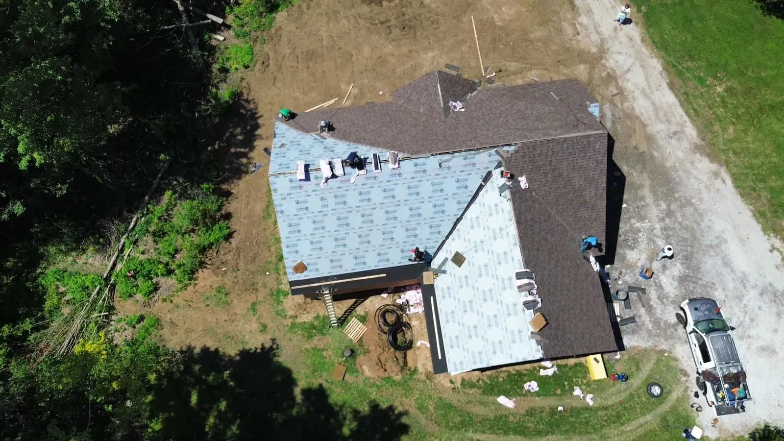 An aerial view of a house under construction with a roof being installed.
