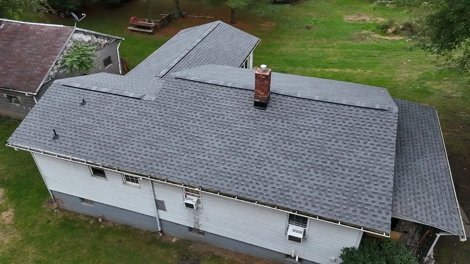 An aerial view of a house with a gray roof and a chimney.