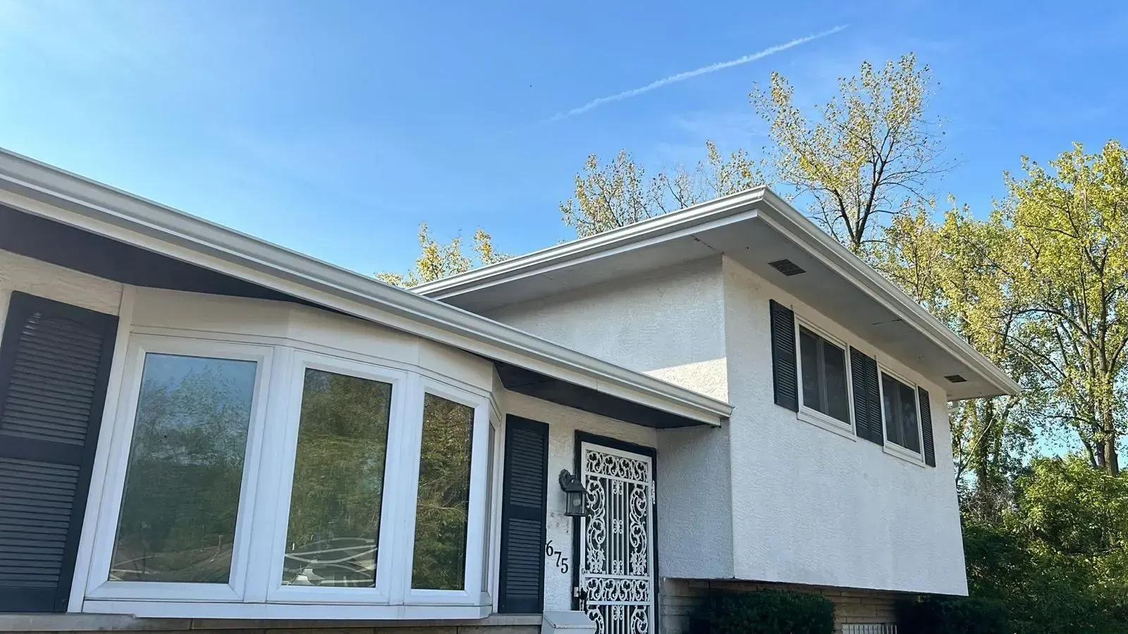 A white house with black shutters and a blue sky in the background.