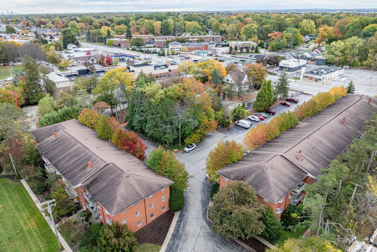 Aerial view of brick apartment buildings surrounded by trees in autumn.