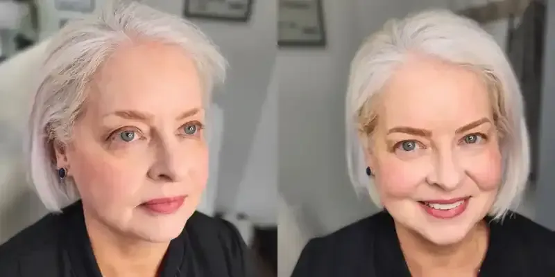 A woman with white hair and a black shirt is smiling.