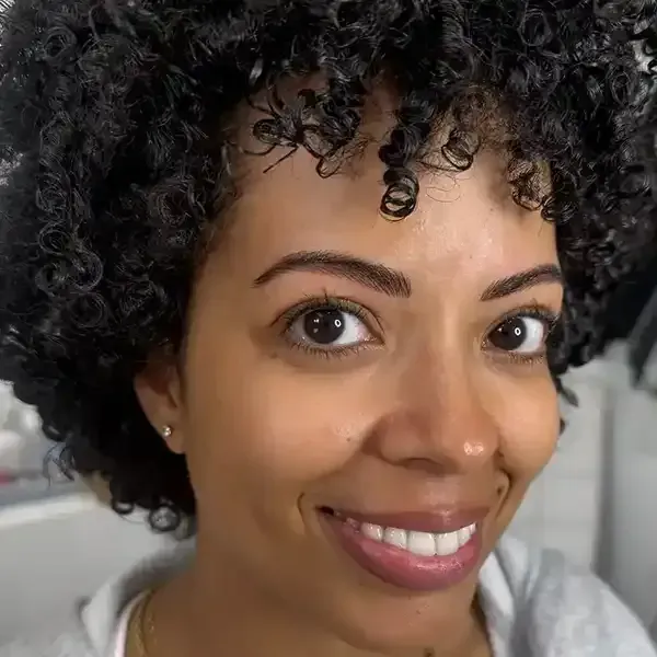 A woman with curly hair is smiling for the camera.