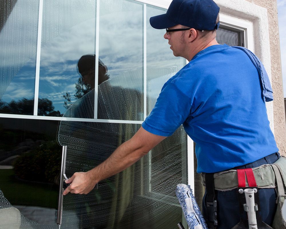 Worker Using Squeegee on Window — Austin, TX — Scout Window Cleaning