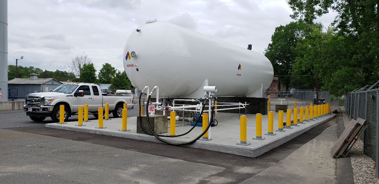A propane tank is sitting in a parking lot next to a truck.