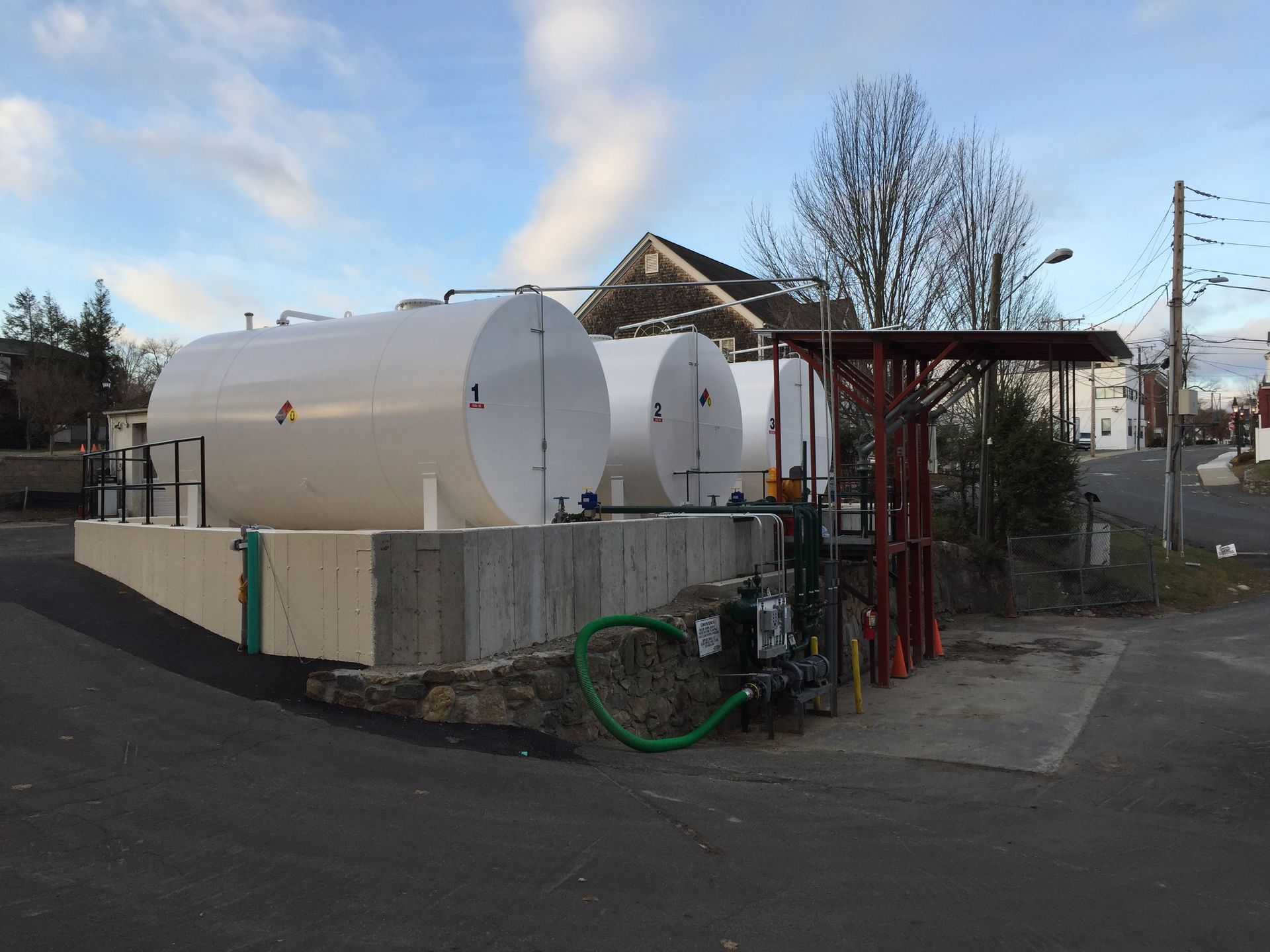 Two large white tanks are sitting next to each other on the side of the road.