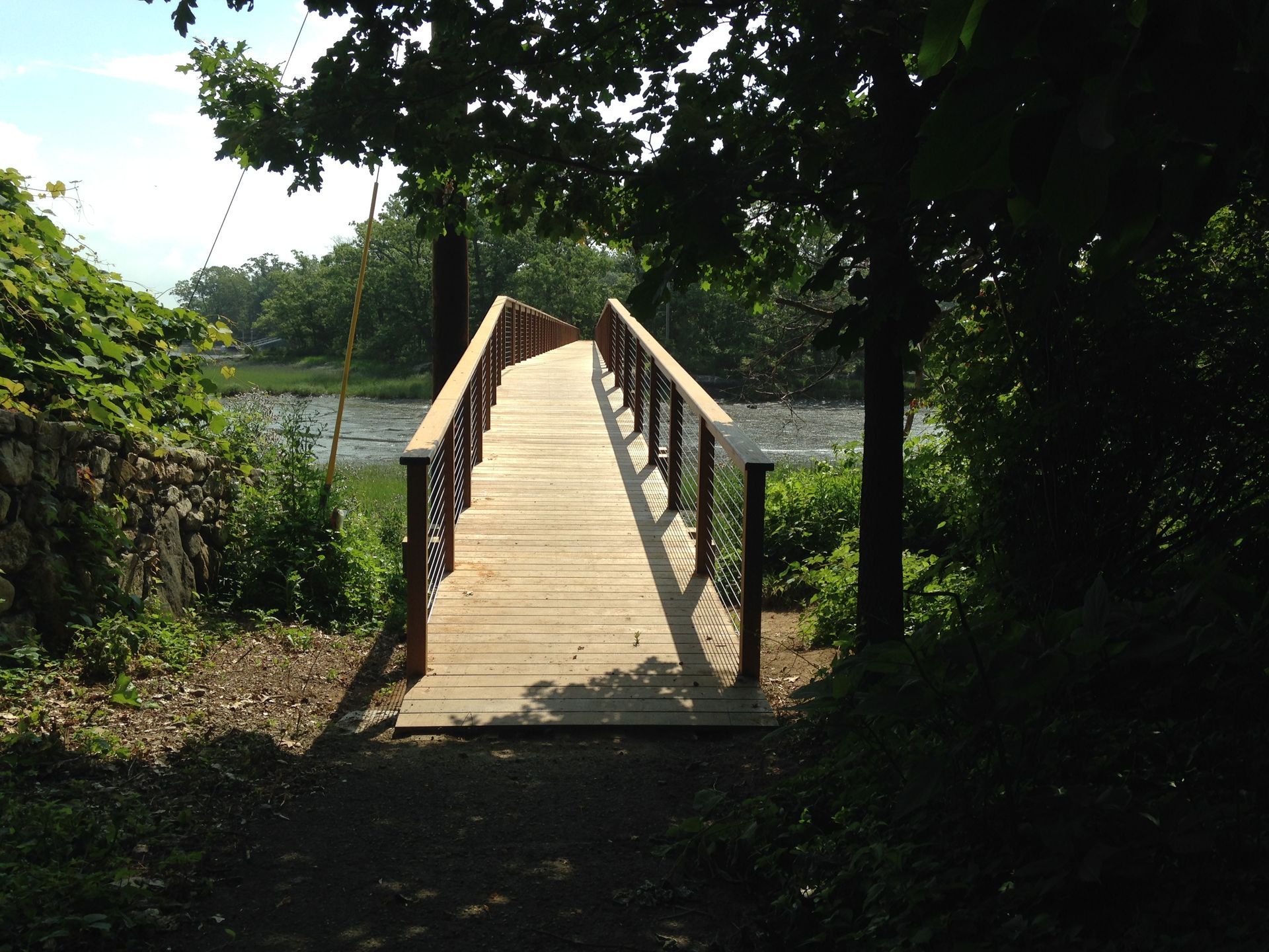 A wooden bridge over a body of water surrounded by trees