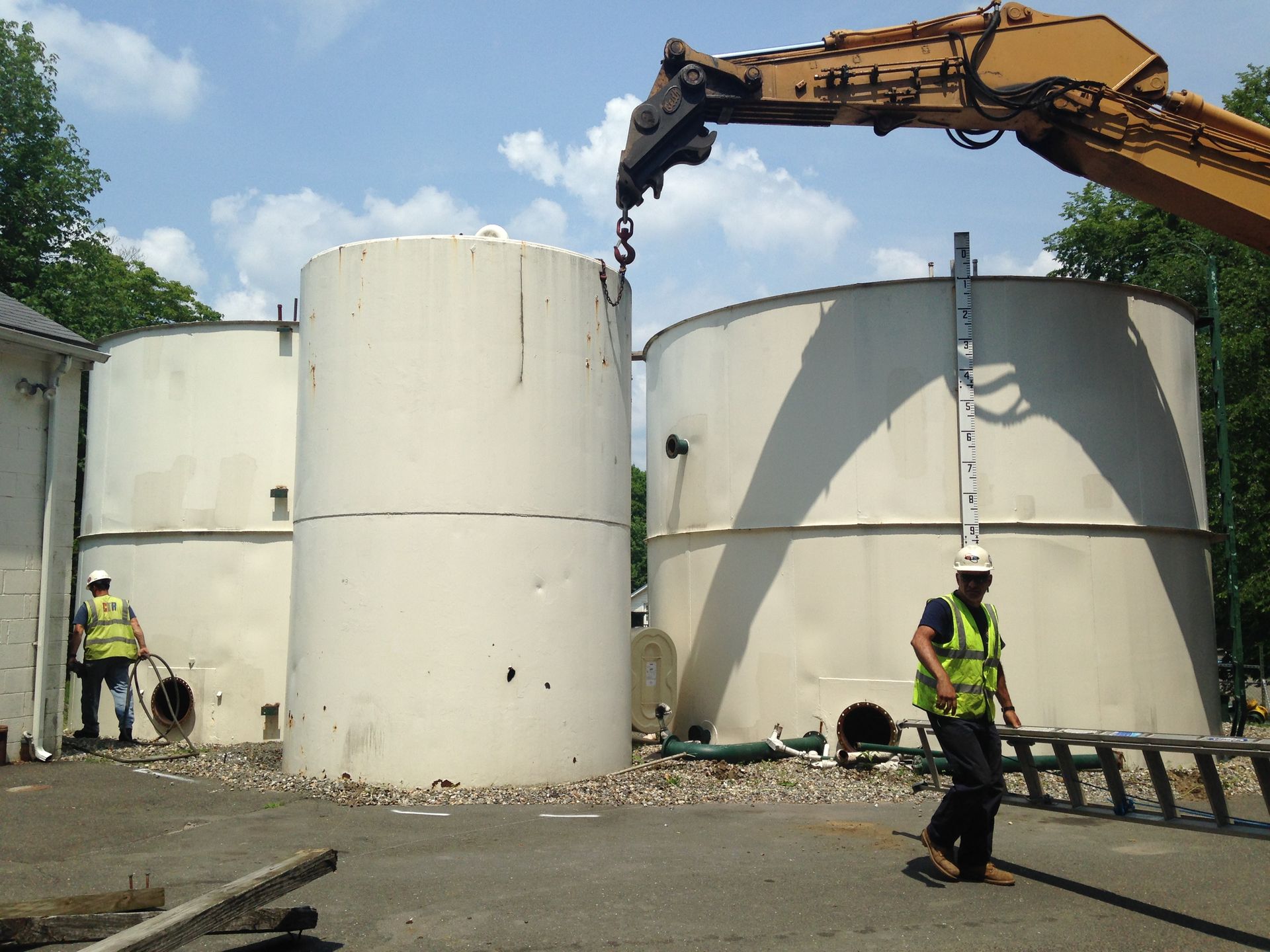A large crane is lifting a large white tank
