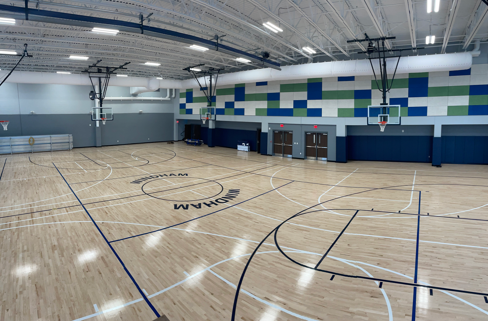 A large indoor basketball court with a wooden floor and a basketball hoop.