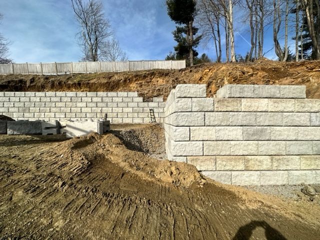 A large brick wall is being built on top of a dirt hill.