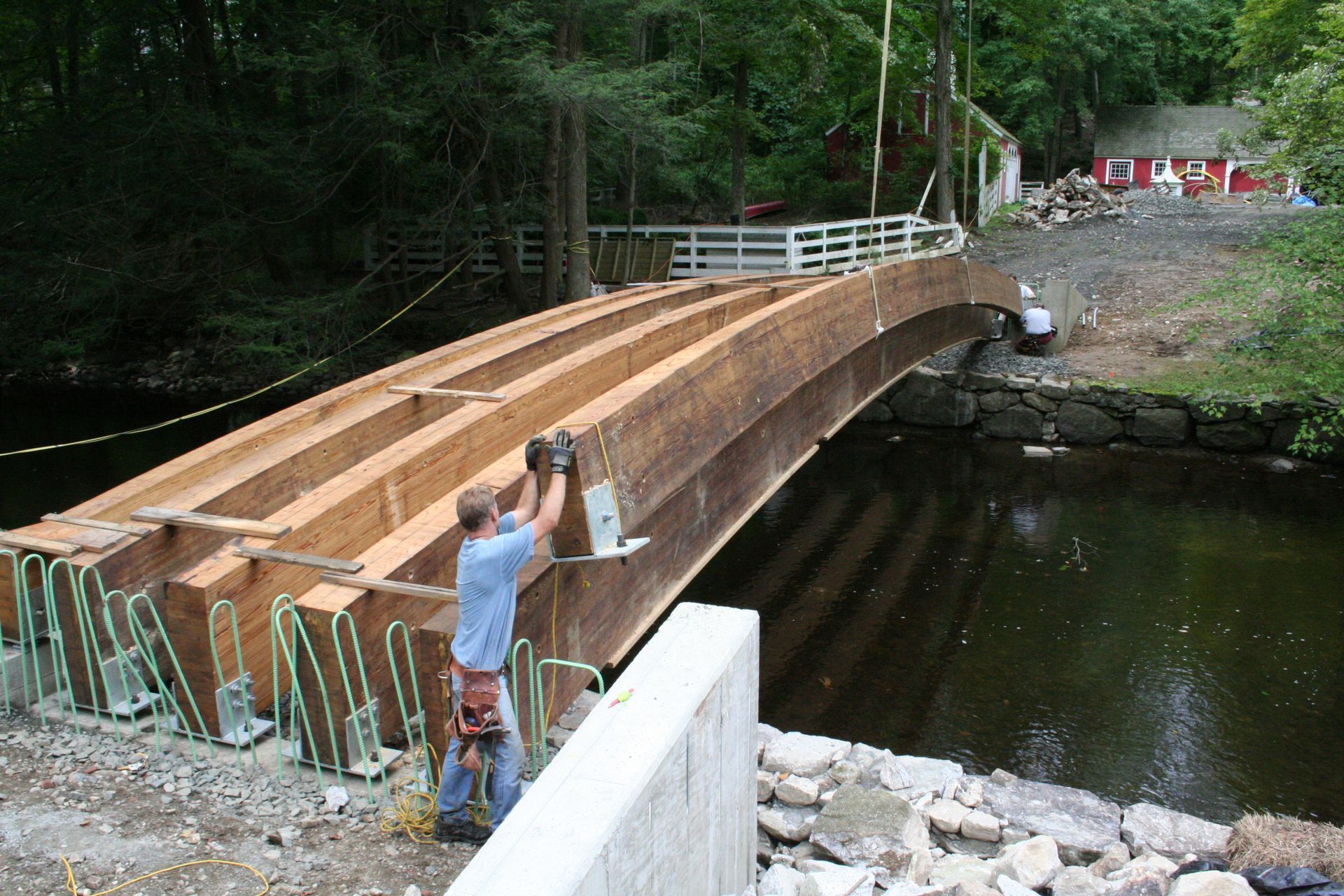 A man is working on a wooden bridge over a river