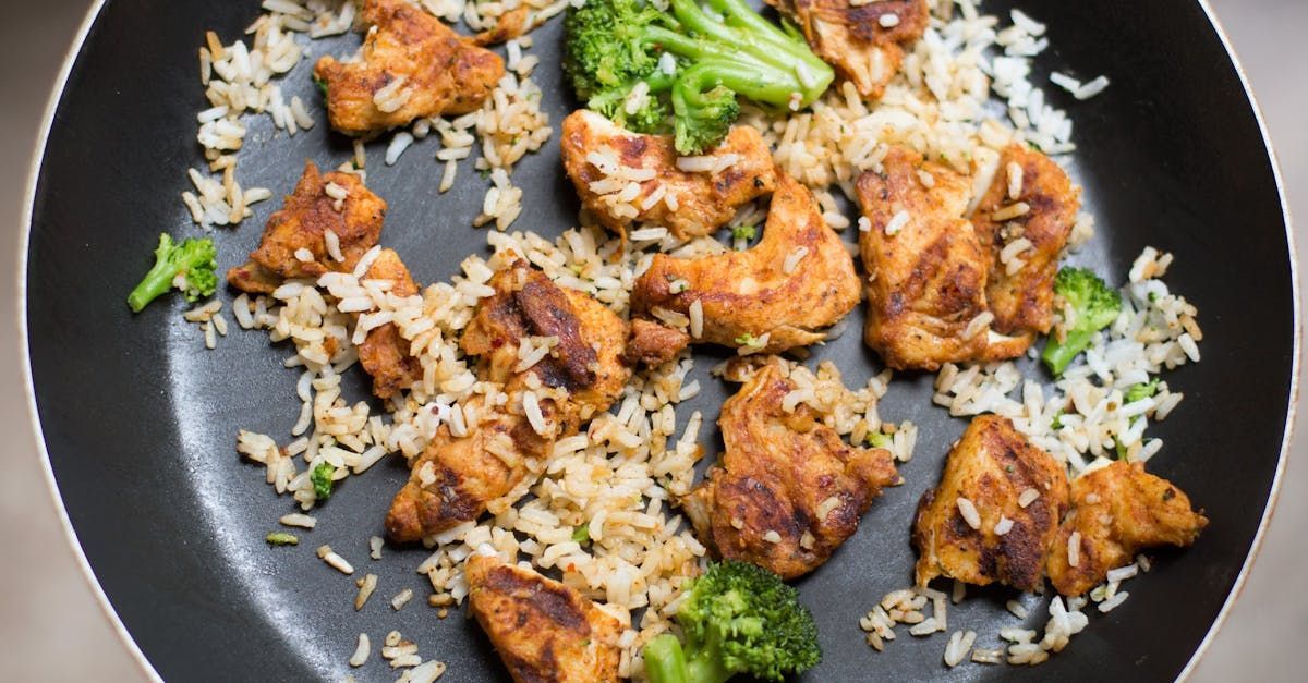 A pan filled with rice , broccoli and chicken.