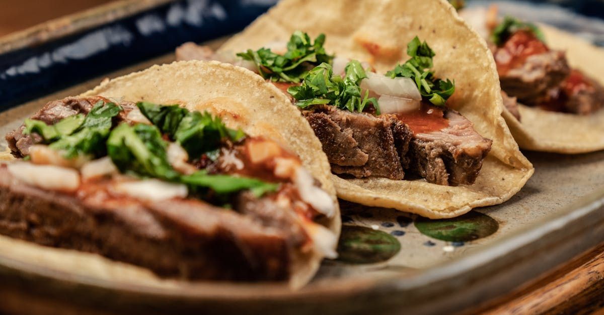 A close up of a plate of tacos with meat and vegetables on a table.