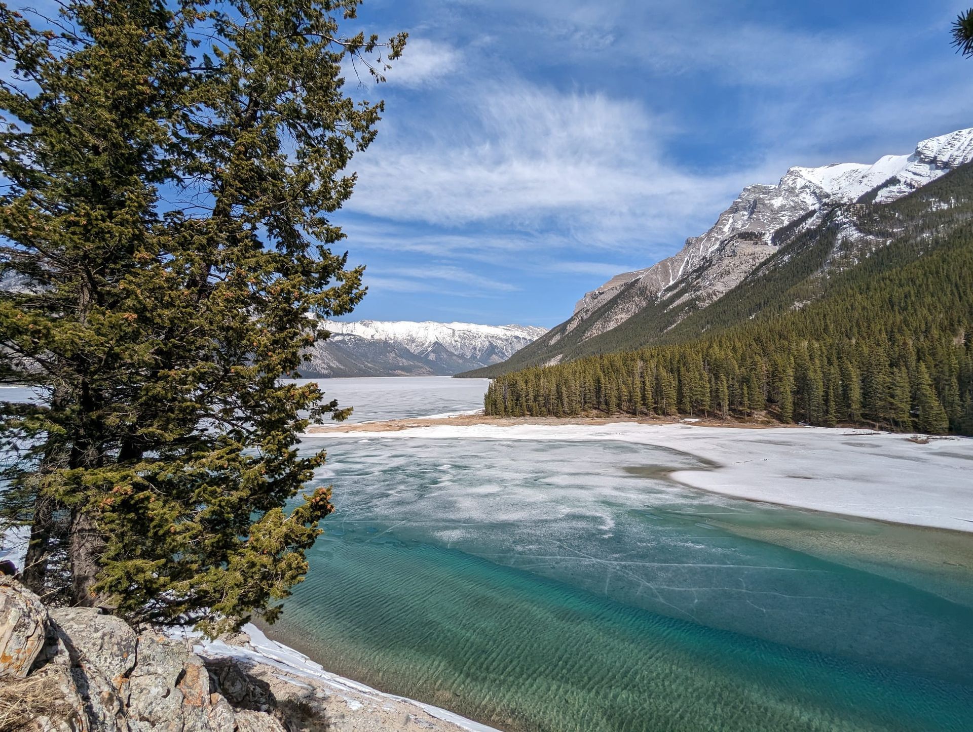 An image of the mountains at Banff, with the frozen river starting to melt and the blue pop.