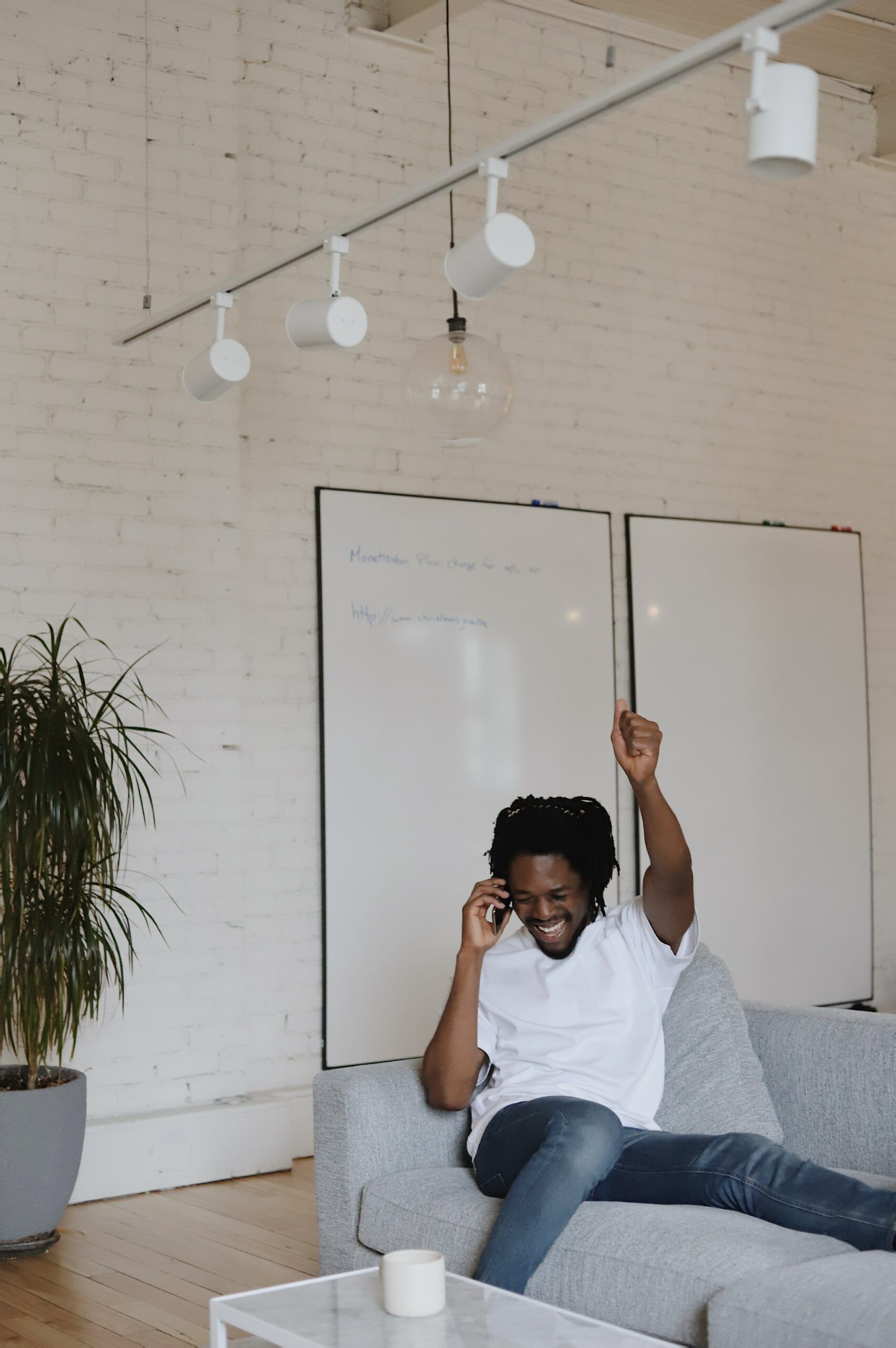 young man on couch excited on phone with fist pump in air