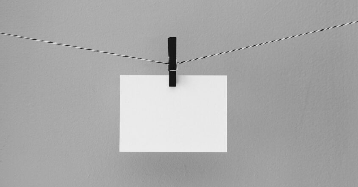 A white card hangs from a cord by a black clothespin