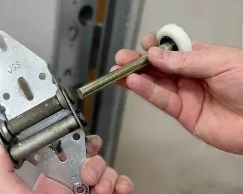 A person is fixing a garage door with a wrench.