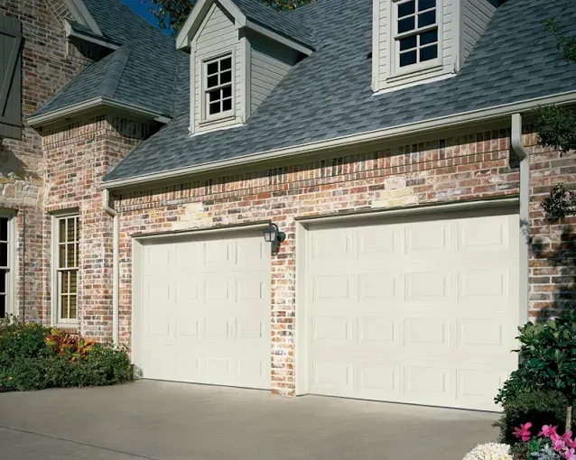 A large brick house with two white garage doors.