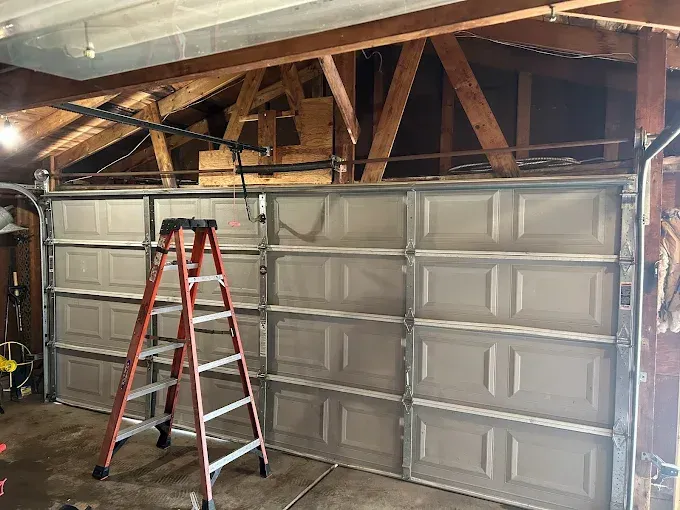 A ladder is sitting next to a garage door in a garage.