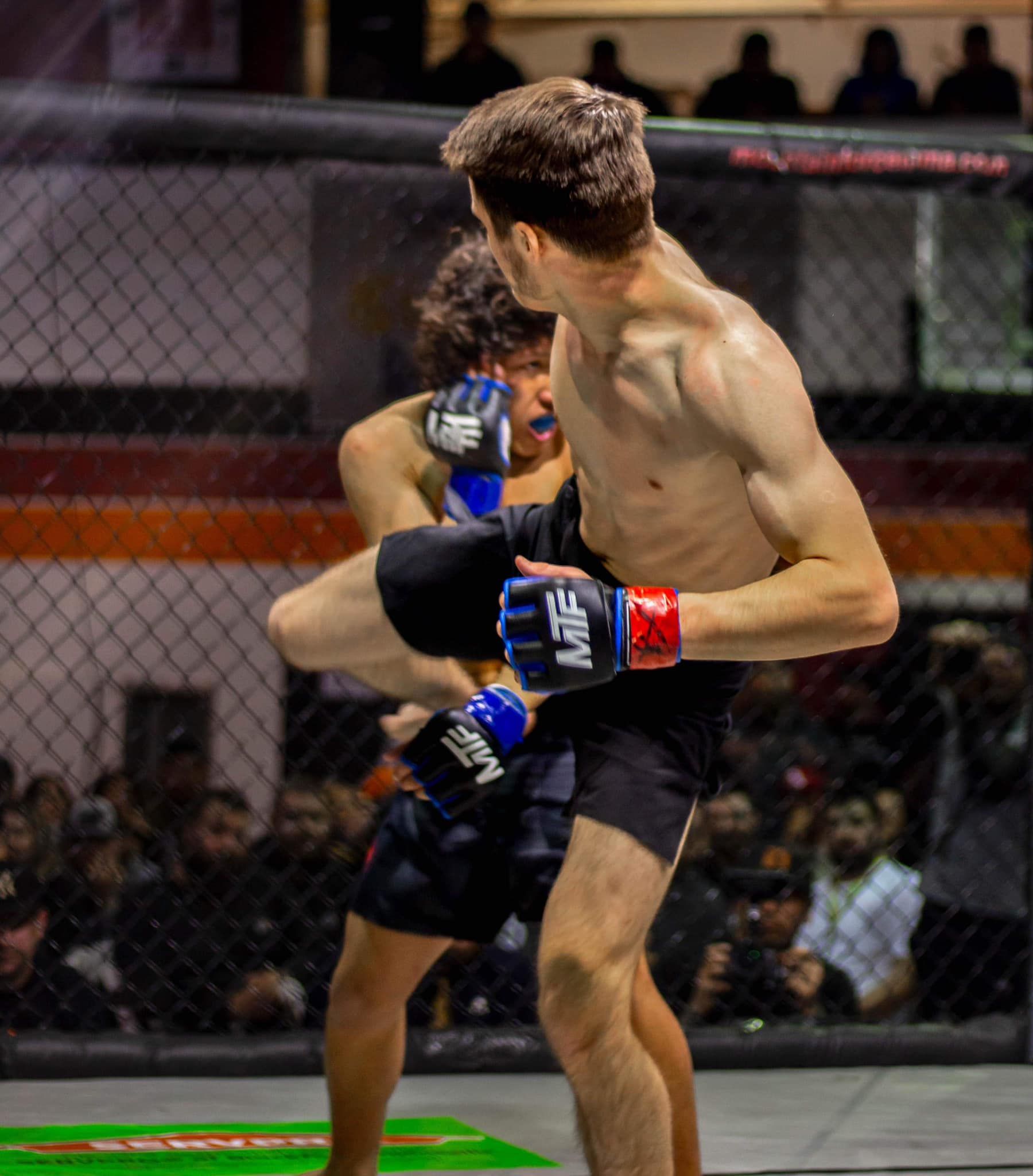 Two men are fighting in a boxing ring and one of them is wearing gloves that say ufc