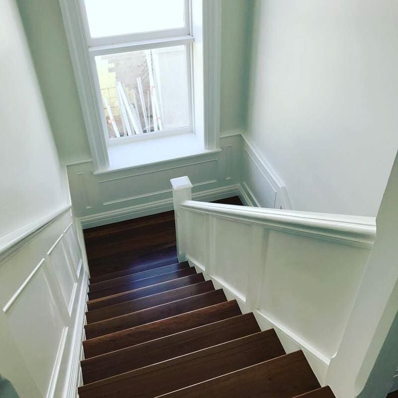 A Wooden Staircase with A White Railing and A Window — Burns Custom Kitchens in Newcastle, NSW
