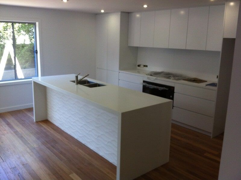 A Kitchen with White Cabinets and A Large Island — Burns Custom Kitchens in Newcastle, NSW