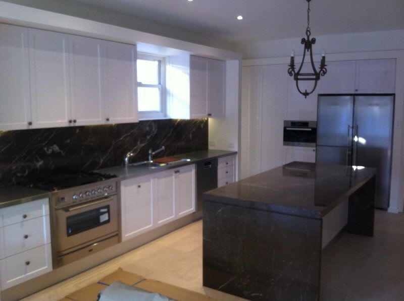 A Kitchen with White Cabinets and Black Counter Tops — Burns Custom Kitchens in Newcastle, NSW