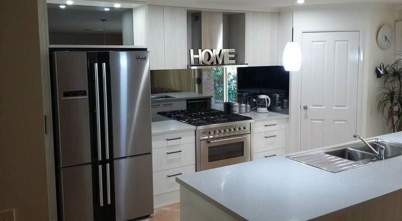 A Kitchen with Stainless Steel Appliances and A Sign that Says Home Above the Refrigerator — Burns Custom Kitchens in Newcastle, NSW