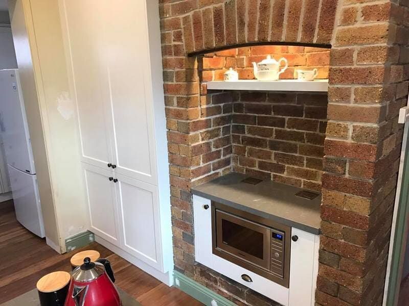 A Kitchen with A Brick Fireplace and A Microwave — Burns Custom Kitchens in Newcastle, NSW