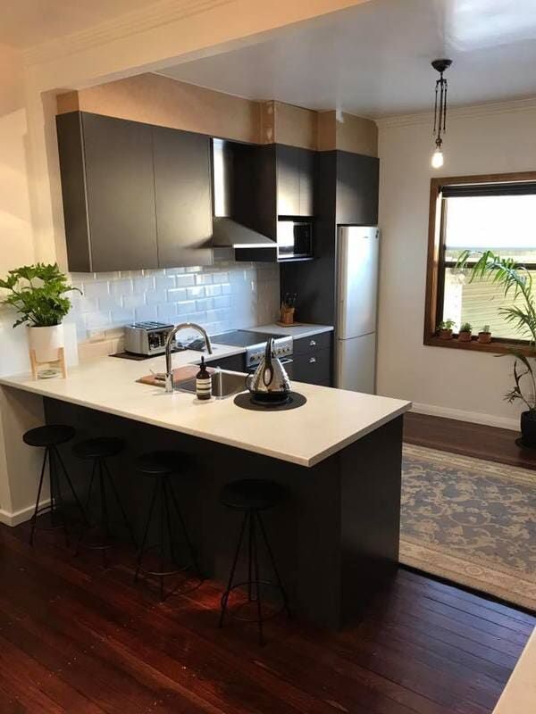 A Kitchen with A Sink, Stove, Refrigerator and Stools — Burns Custom Kitchens in Newcastle, NSW