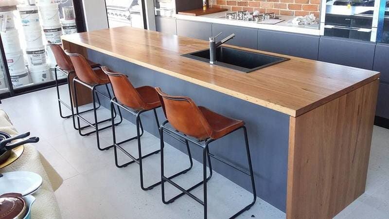 A Kitchen with A Long Wooden Counter Top and Stools — Burns Custom Kitchens in Newcastle, NSW