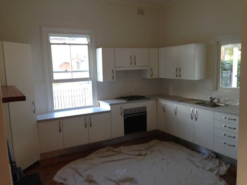 An Empty Kitchen with White Cabinets and A Window — Burns Custom Kitchens in Newcastle, NSW
