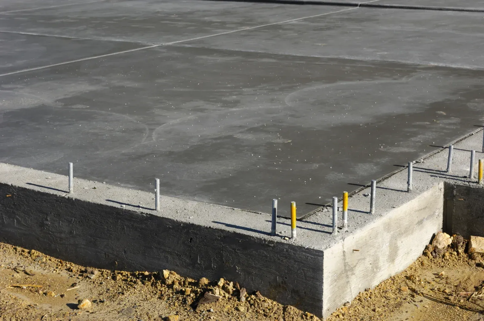 Concrete foundation slab with rebar protruding at the edge on a construction site