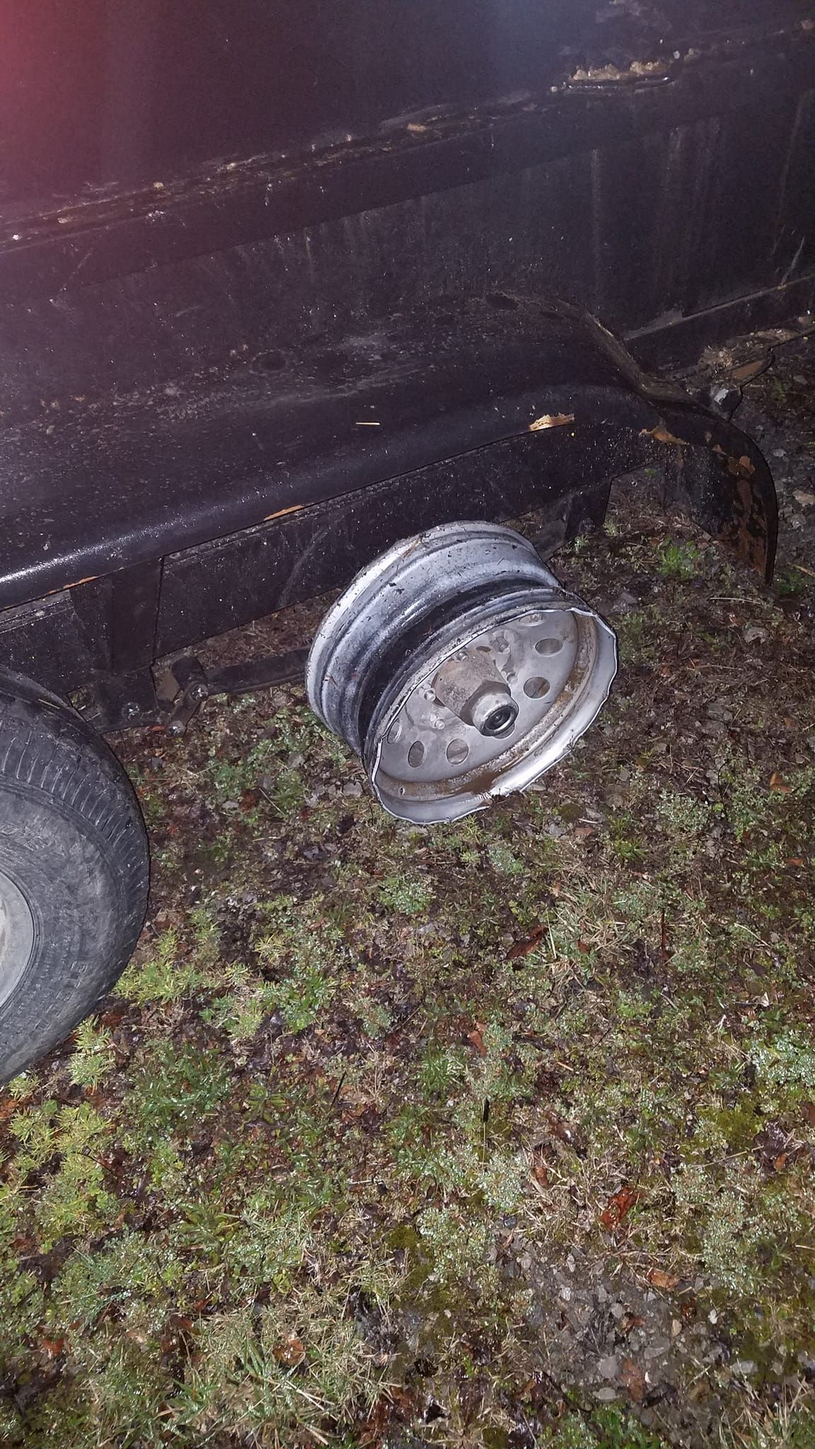 Black vehicle with a detached wheel on grass.