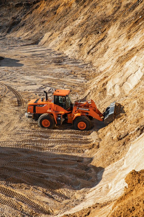 Orange wheel loader in a sand pit, moving earth.
