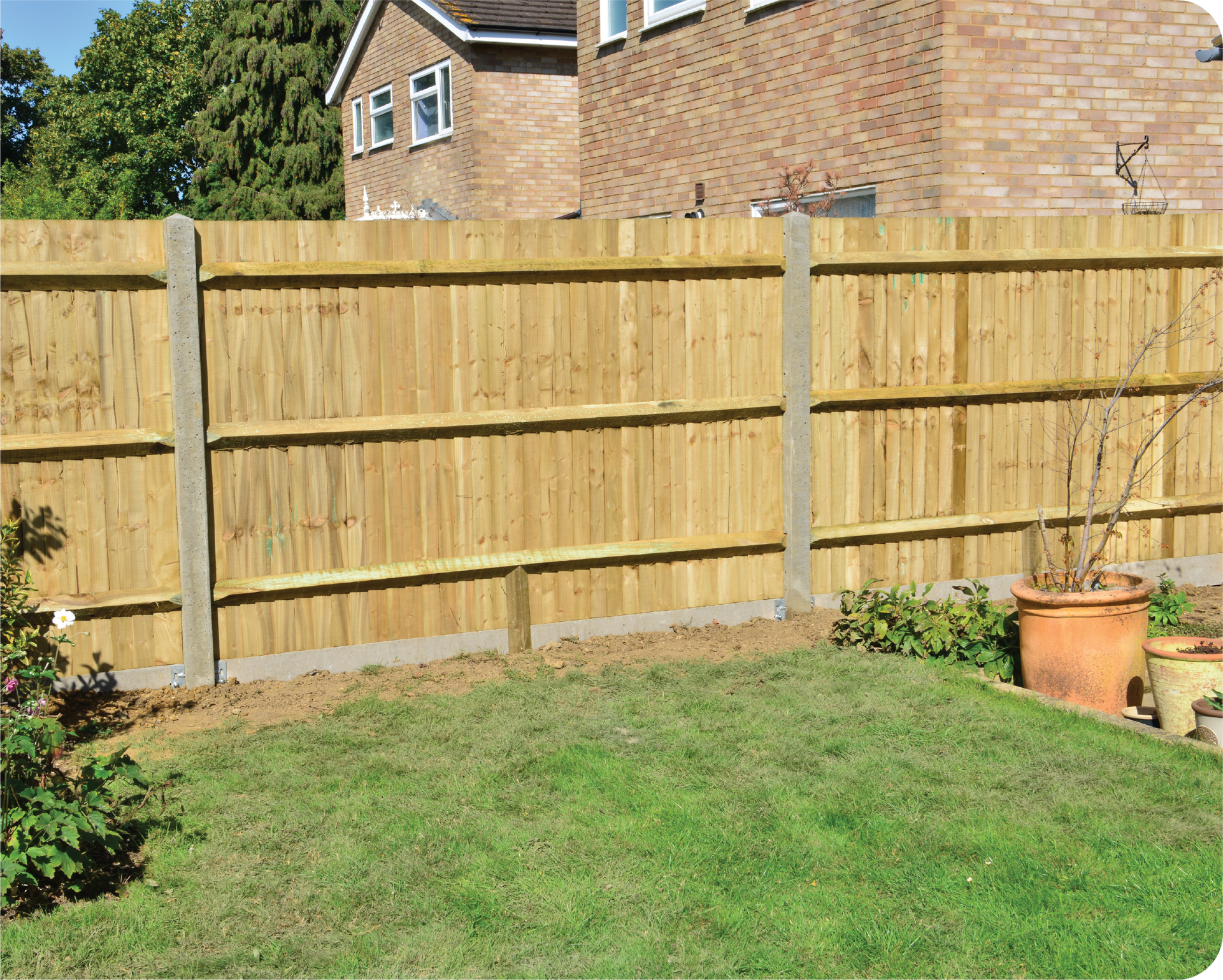 A wooden fence surrounds a lush green lawn in a backyard.