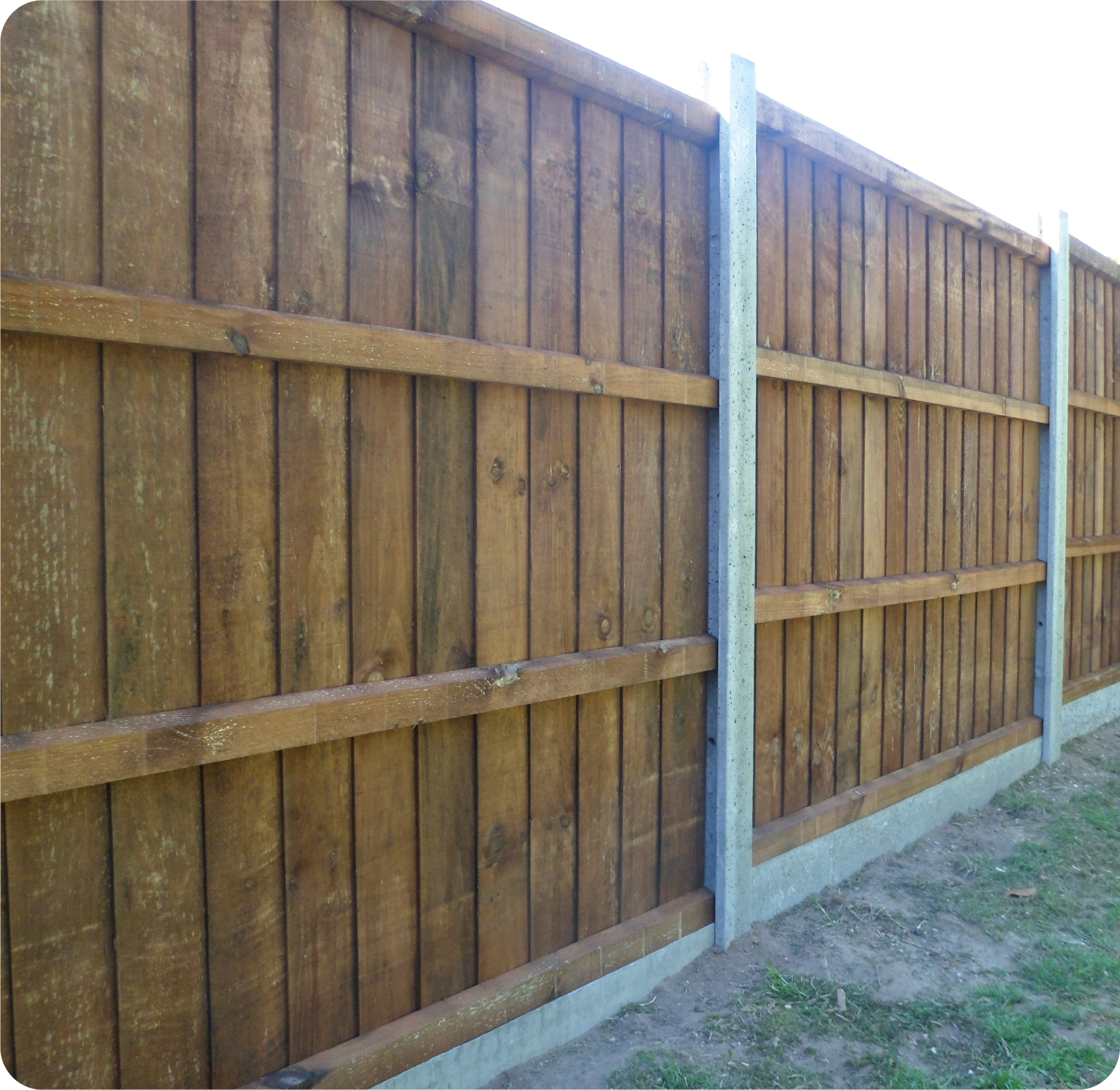 A wooden fence with a concrete post in the middle