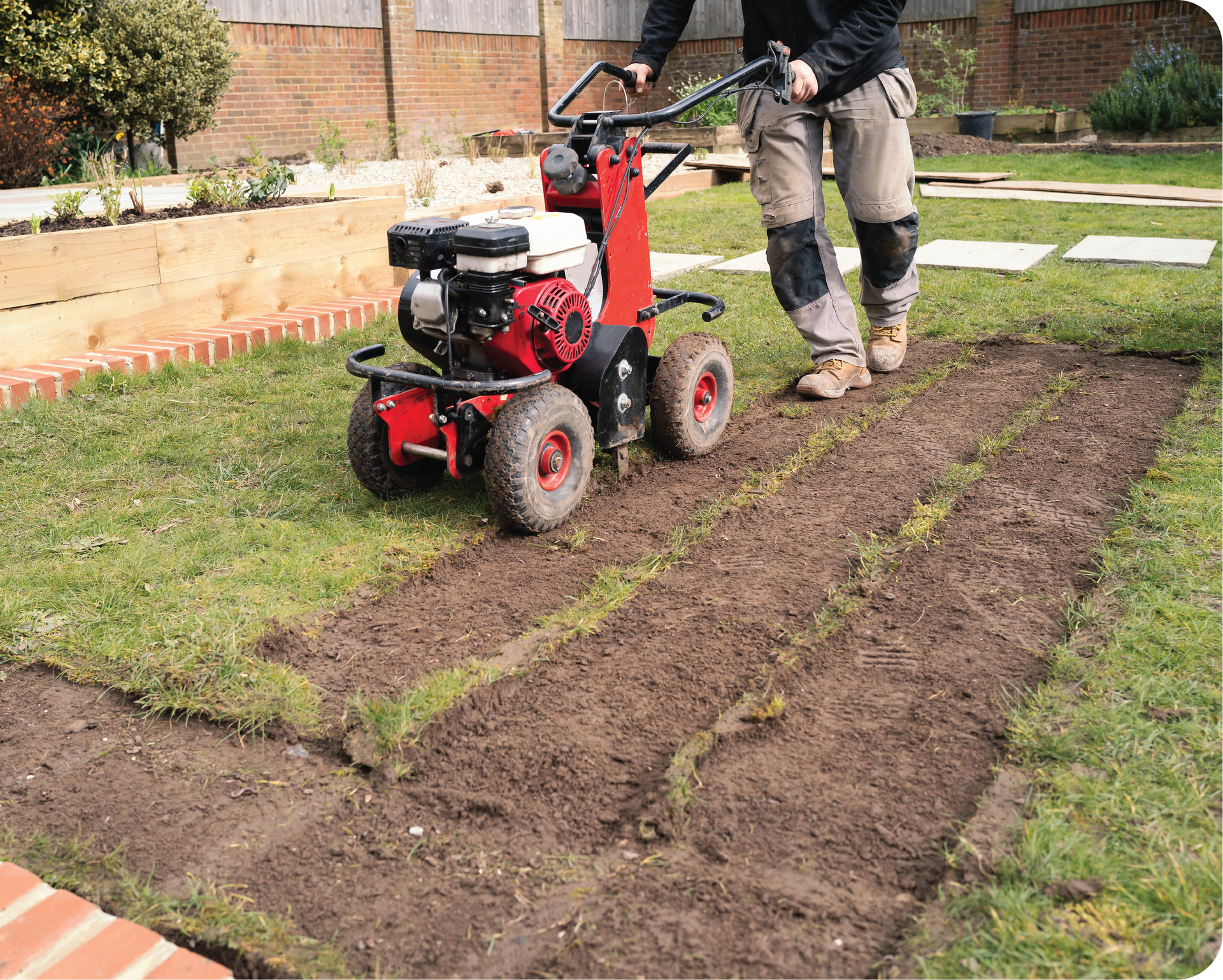 A man is using a machine to cut grass in a yard.