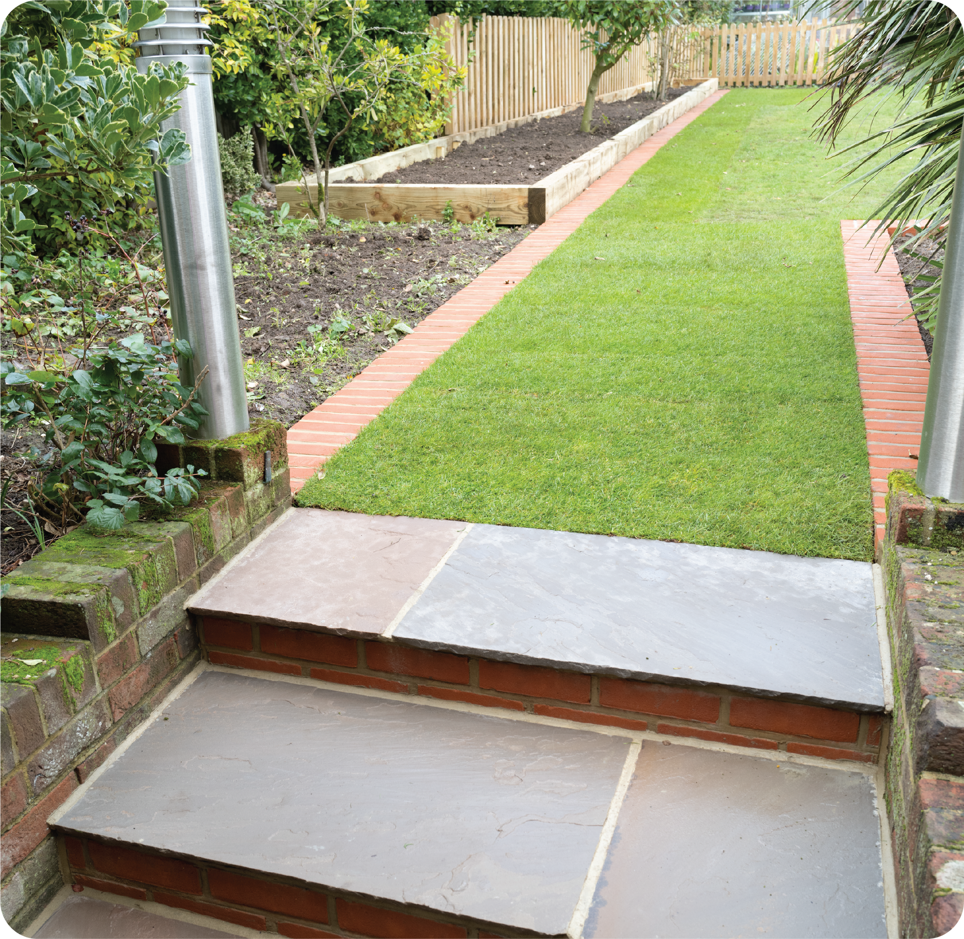 A brick walkway leading to a lush green lawn