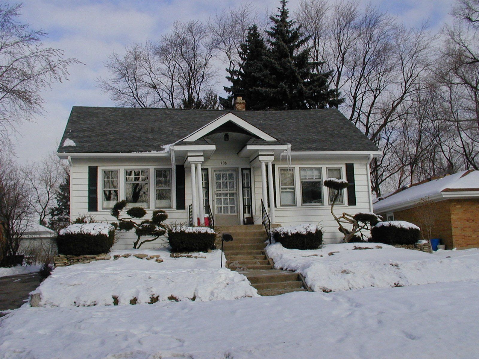 A white house with a gray roof is covered in snow