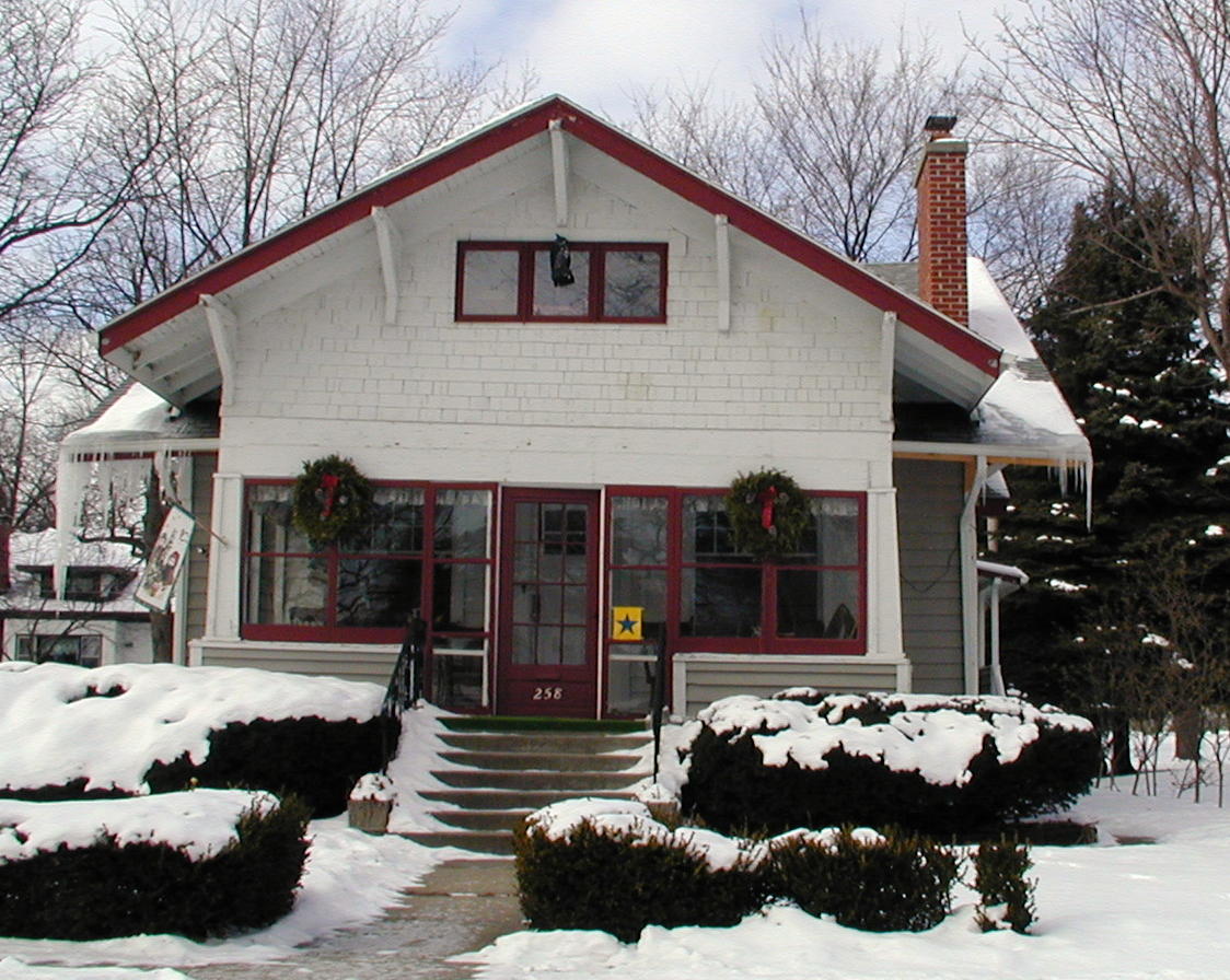 A white house with a red roof is covered in snow