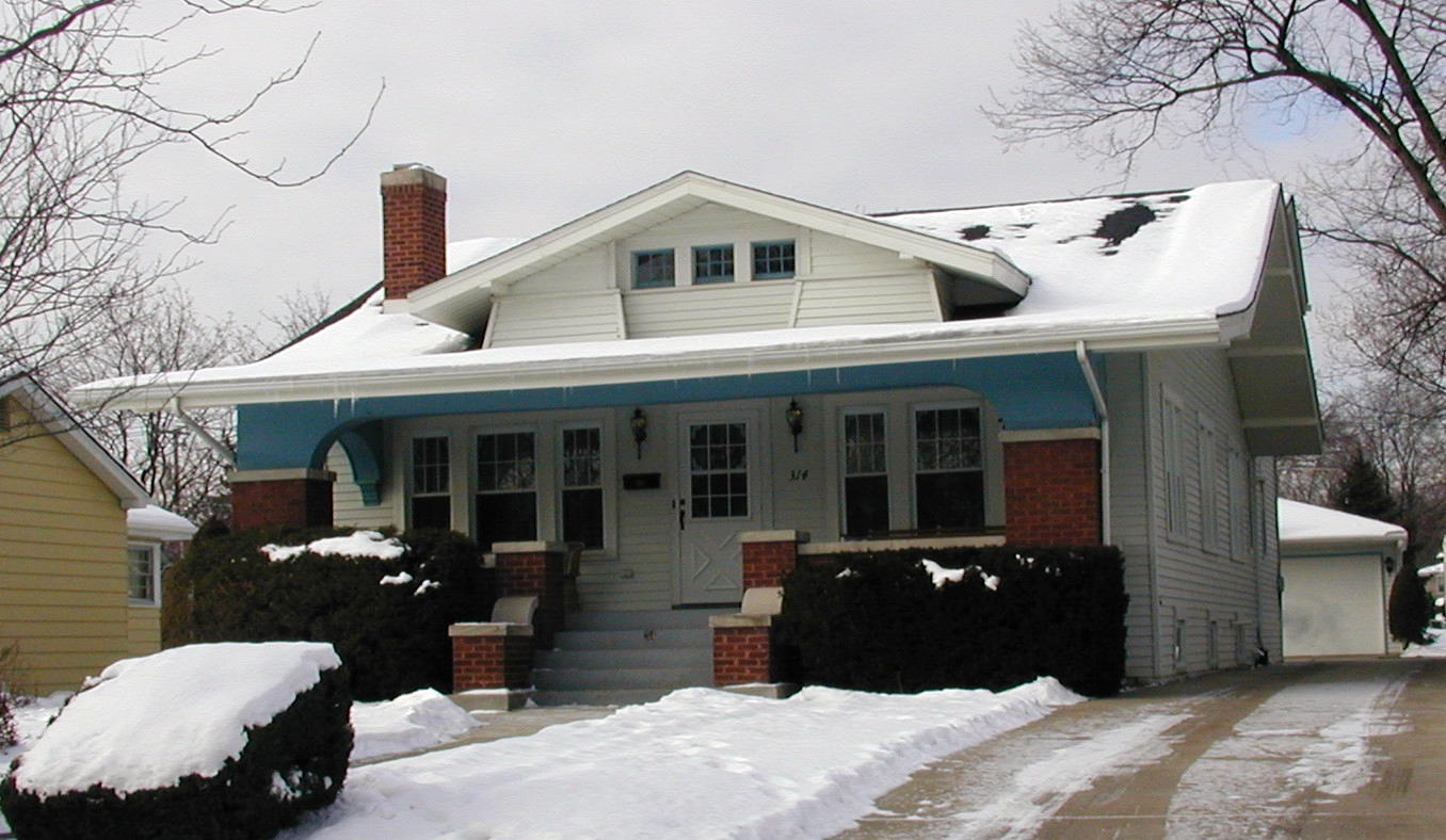 A snowy house with a car parked in front of it