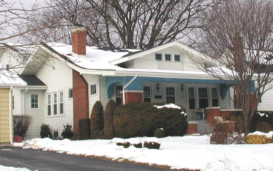 A house with a chimney on the roof is covered in snow