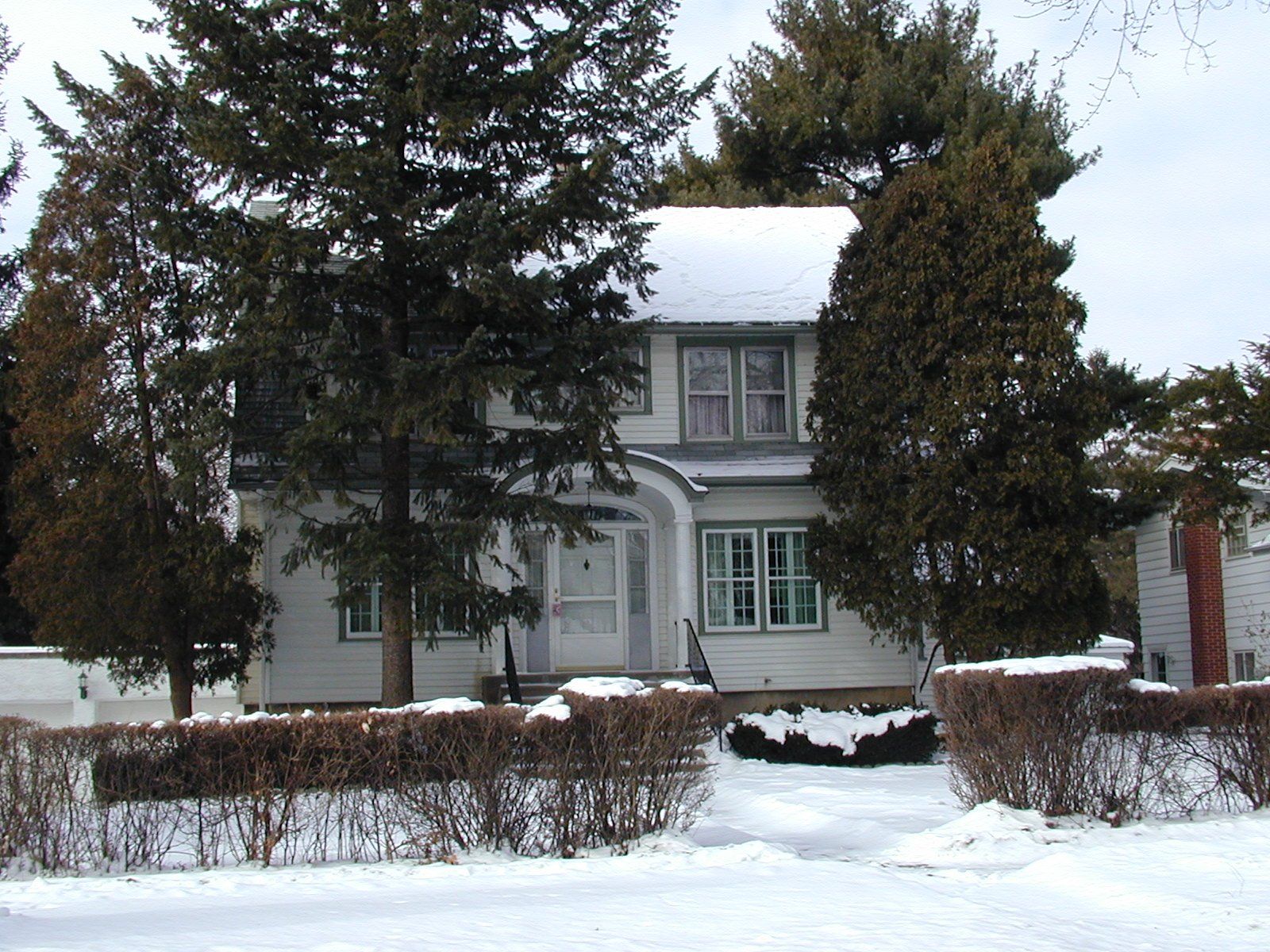 A snowy house with trees in front of it