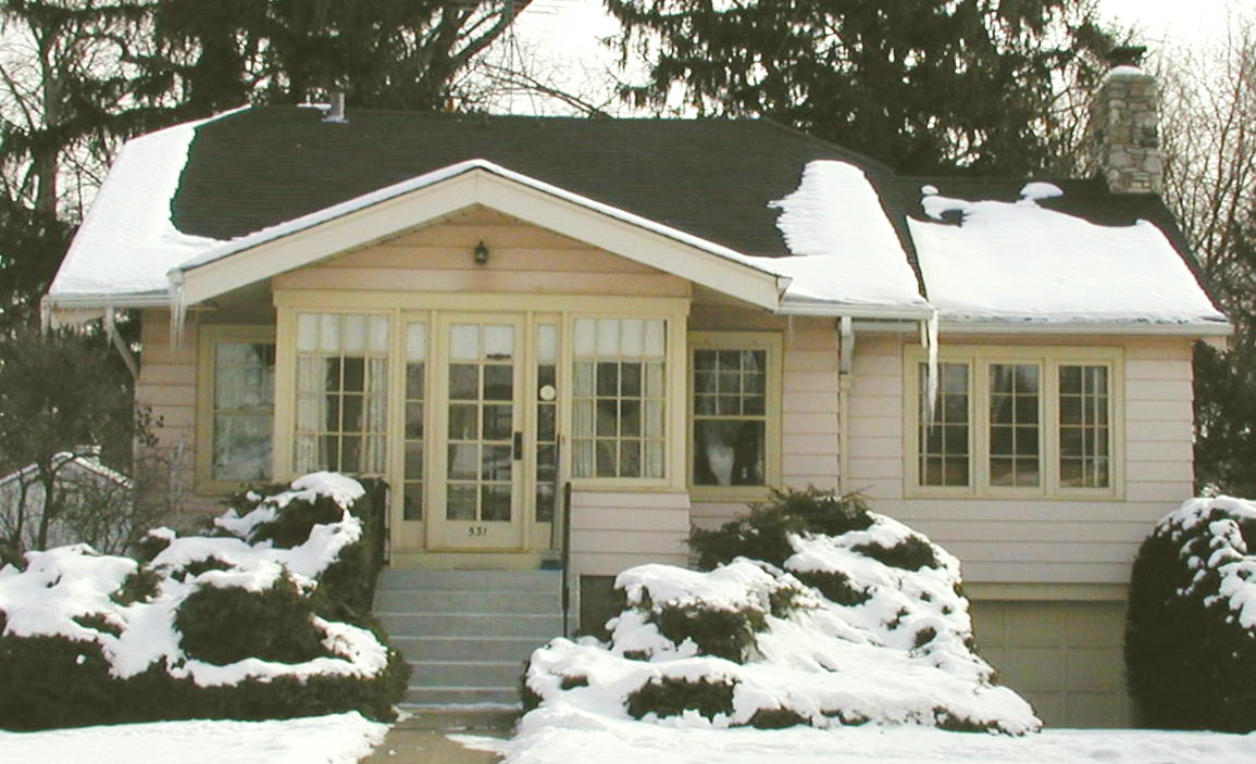 A house with a black roof is covered in snow