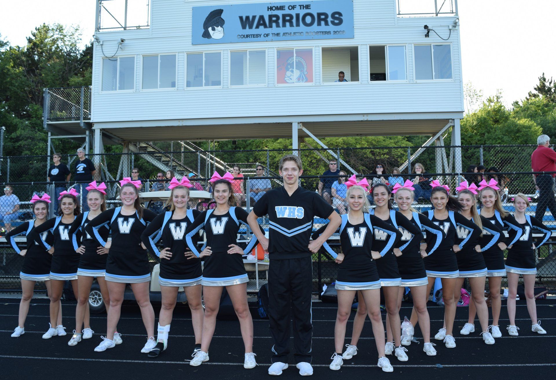 A group of cheerleaders are posing for a picture in front of a warriors stadium