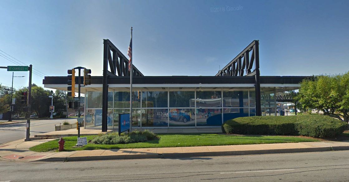 A large building with a lot of windows is sitting on the corner of a street.