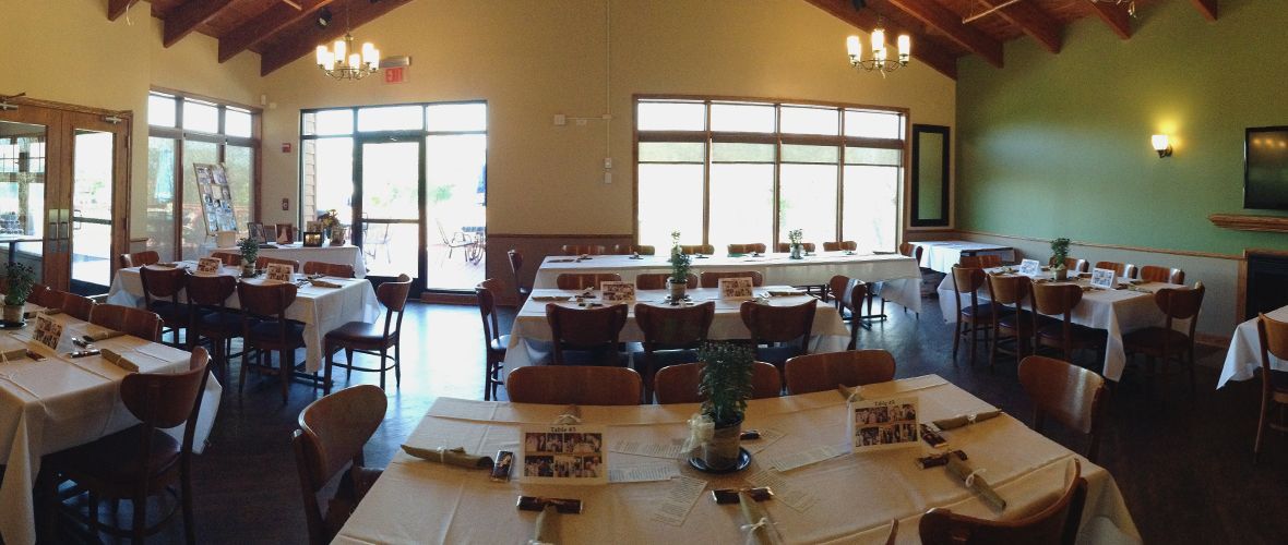 A large dining room with tables and chairs set up for a wedding reception.