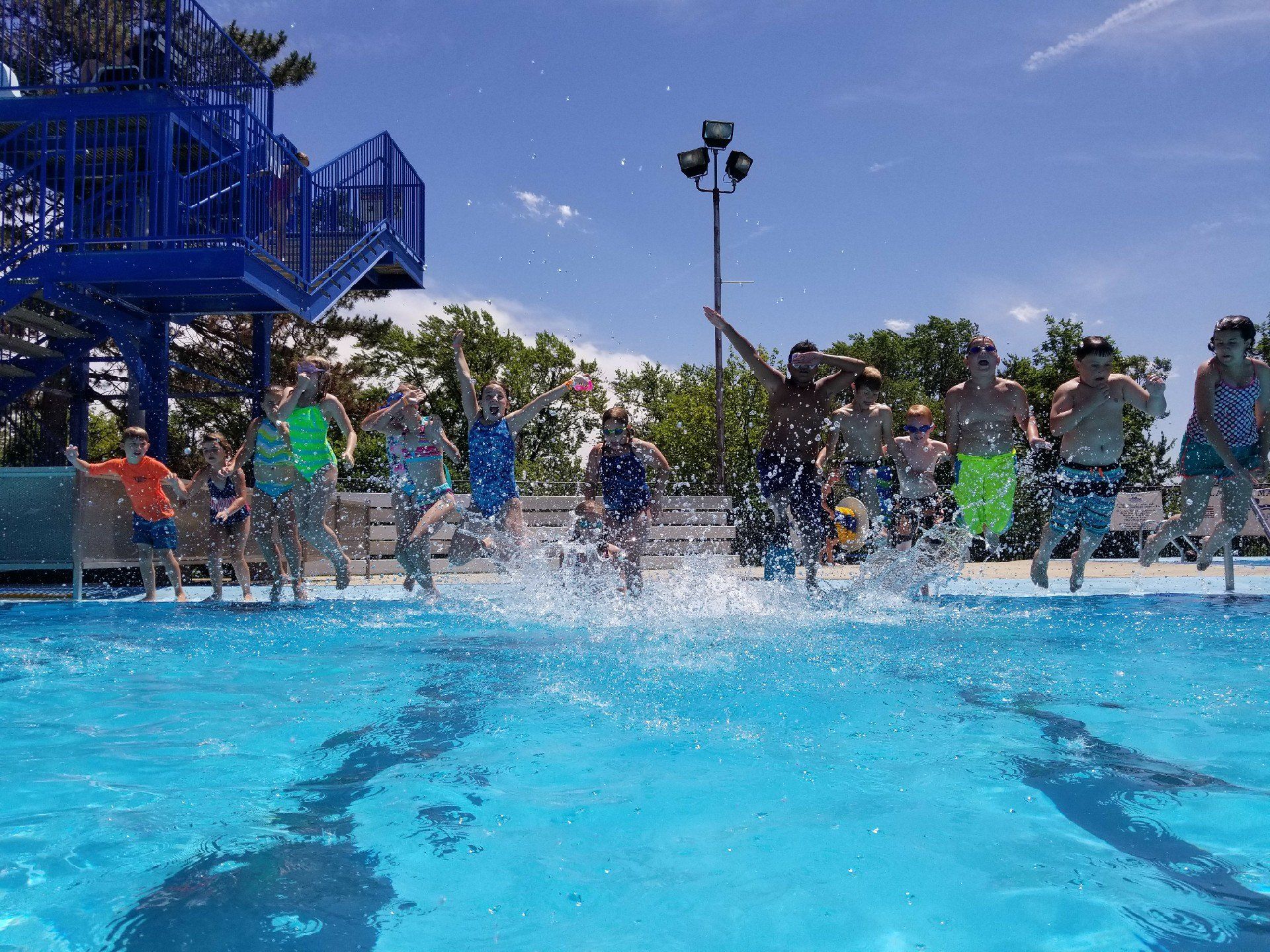 A group of people are jumping into a swimming pool.