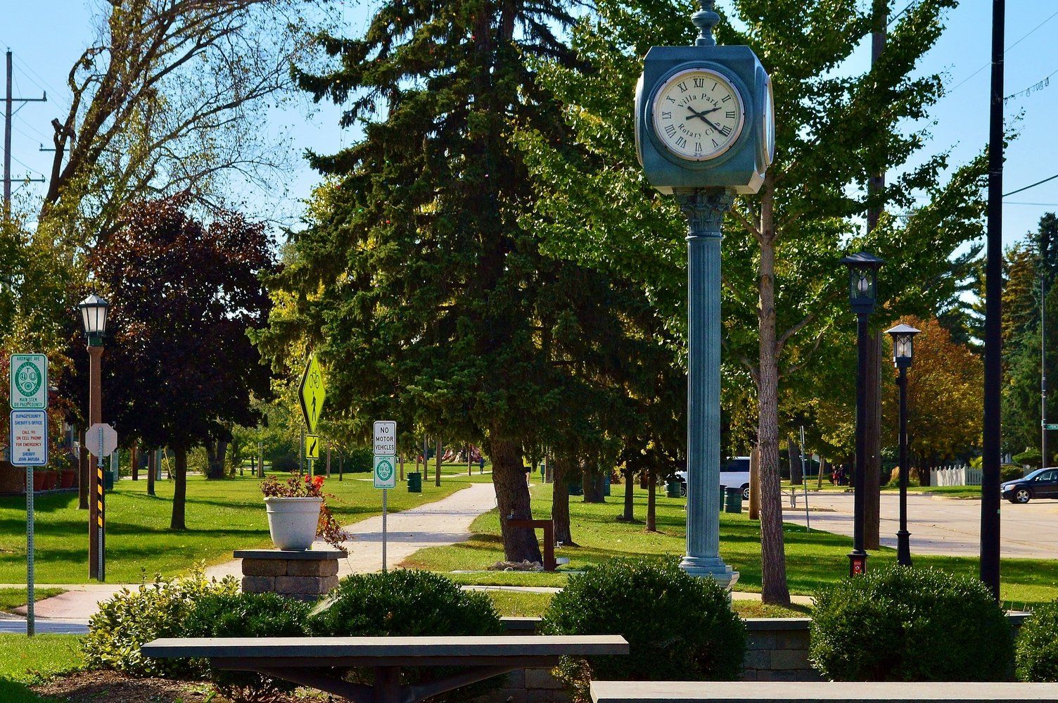 A clock tower in a park with a sign that says no parking